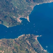 An aerial view of a narrow waterway between two larger bodies of water.