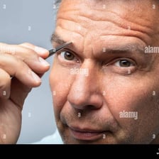 A person grooming an eyebrow with tweezers