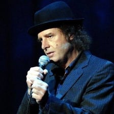 Steven Wright performing stand-up comedy with an understated expression