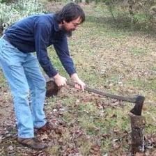 A person using an ax to cut a piece of wood