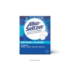 Effervescent Alka-Seltzer tablets dissolving in a glass of water.