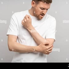 A person holding an injured hand and showing physical pain.