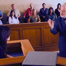 A witness gives testimony from a courtroom stand.
