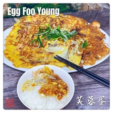 A Chinese-American egg foo young omelet served with gravy and vegetables