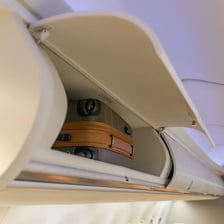 An airplane overhead compartment containing carry-on luggage