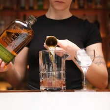 A bartender pouring a double measure into a glass