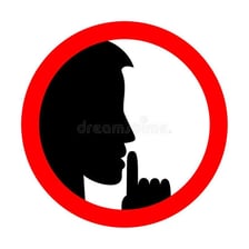 A person holding a finger to their lips to signal silence