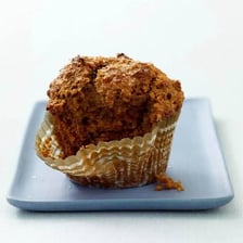 A bran muffin beside wheat bran and grain.