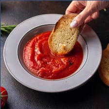 Piece of bread absorbing sauce from a dish