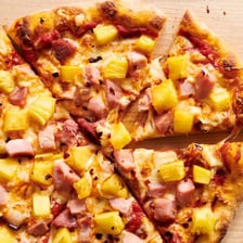 A Hawaiian pizza topped with ham and pineapple