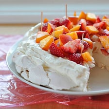 A cake being coated with icing using a spatula.