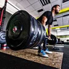 A person performing a heavy weightlifting exercise in a gym.