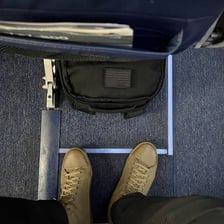 A carry-on bag placed beneath an airplane seat