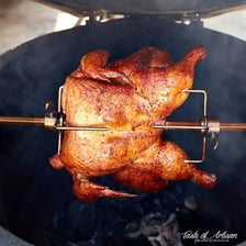 Chicken turning on a metal rotisserie spit.
