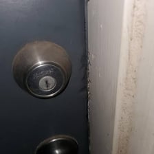 A person using a tool to pry open a door.