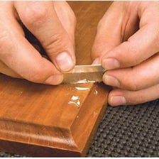 A person applying a layer of lacquer to a wooden surface.
