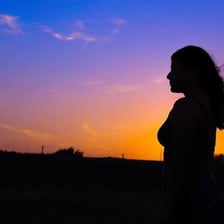 A dark silhouette standing in front of a bright sunset.