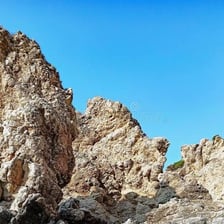 A jagged rocky crag rising above a natural landscape.