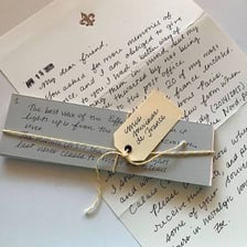 A hand forming written letters on a sheet of paper.