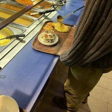 A person filling a plate with a large amount of food.