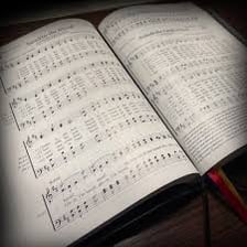 An open Bible displaying the Book of Psalms beside a hymn book.
