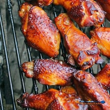 Chicken wings cooking in a smoker over wood smoke