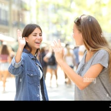 Two friends greet each other in a casual setting.
