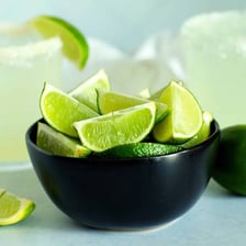 A bartender using lime wedges as drink garnishes