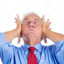 A person covering their ears while enduring a loud sound
