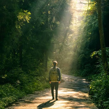 A person walking along an open road with no visible obstacles.