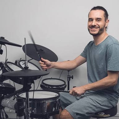 A drummer striking a drum in a regular rhythm.