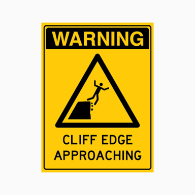A hiker stands close to the edge of an unstable cliff.