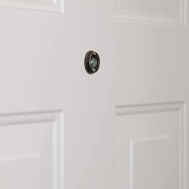 A close-up of a peephole installed in a door.
