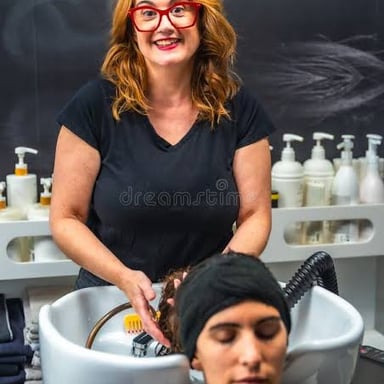 A stylist washes a client's hair at a salon basin.