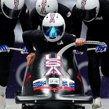 A four-person crew racing in a bobsled on an ice track.