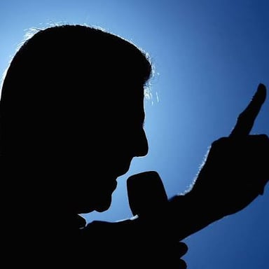 A presenter gesturing while speaking to an audience.