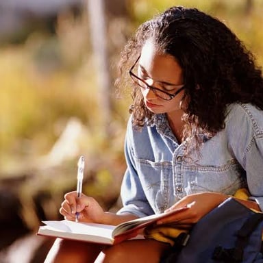 A person writing by hand in a personal journal.