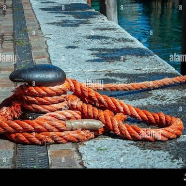A boat held in place on the water by its anchor.