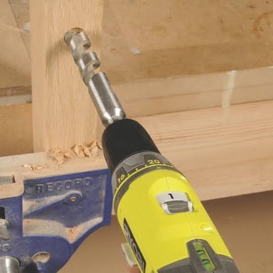 A power drill making a hole in a piece of wood.