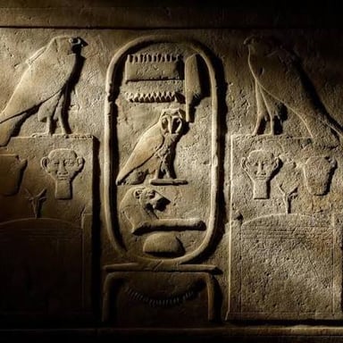 Picture-like hieroglyphic symbols carved into an ancient stone surface.