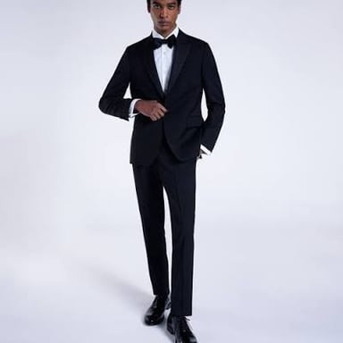 A man wears a black tuxedo with a formal dinner jacket.