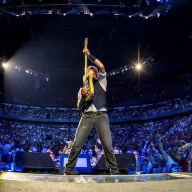 Bruce Springsteen performing onstage with a guitar.