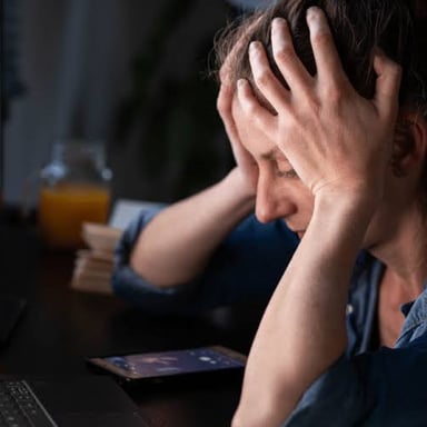 A person looking concerned while sitting with their head in their hands.