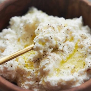 A bowl of soft white ricotta cheese.