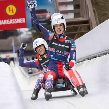 A luge athlete racing feet-first on a sled down an icy track.