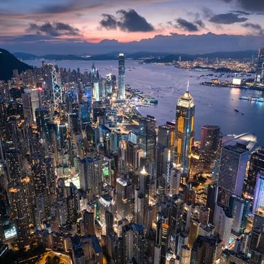 A tall skyscraper rising above surrounding city buildings.