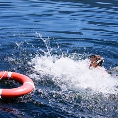 A person in the water beside a boat after going overboard.