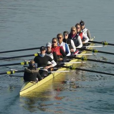 Rowers propelling narrow shells across a river.