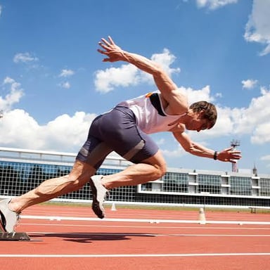 Runners sprinting in a race on an athletics track.
