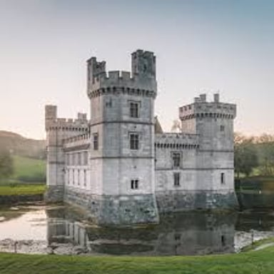 A stone castle with several towers rising above its walls.